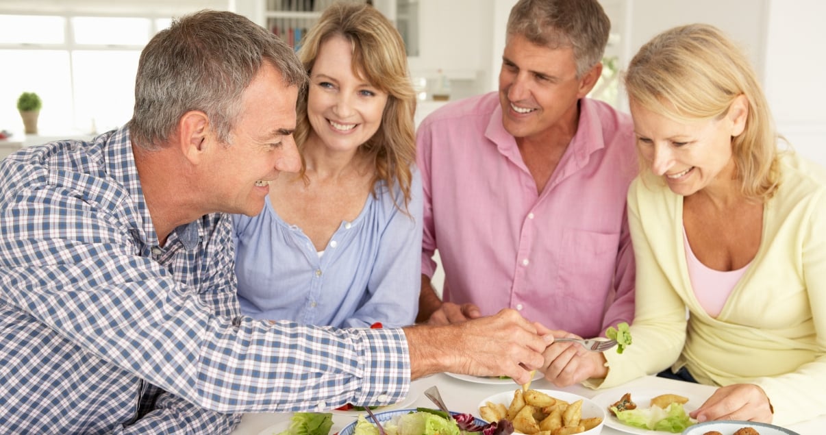 middle aged friends sharing food over table