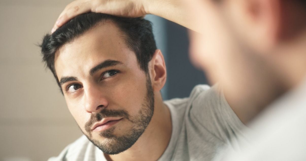 worried_white_young_man_looking_at_mirror_his_receding_hairline