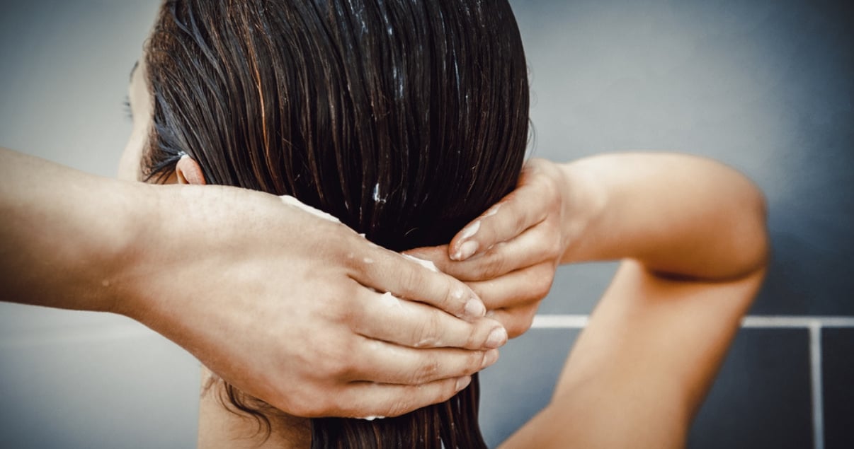 Brunette putting homemade deep conditioner on wet hair in the shower