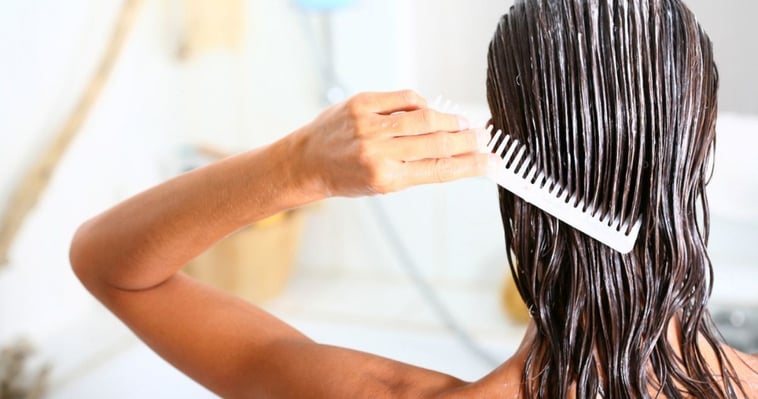 woman brushing hair care product in wet hair