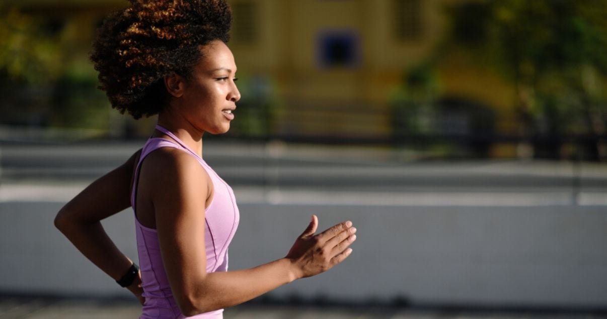 woman of color working out with a hair system in pink shirt