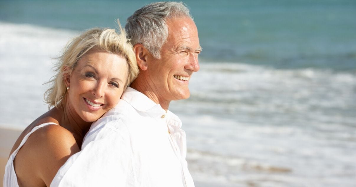 mature couple on beach preventing oxidation by taking hair system care precautions