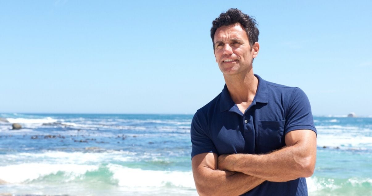 mature man at the beach using hair system care tips to prevent oxidation to his hairpiece while on vacation