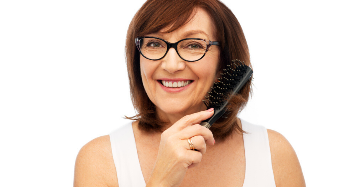 mature woman changing her hair system style with a brush 