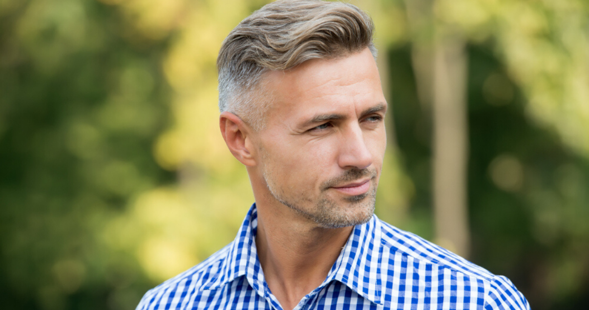 Mature man practicing hair system maintenance to extend the life of his hairpiece