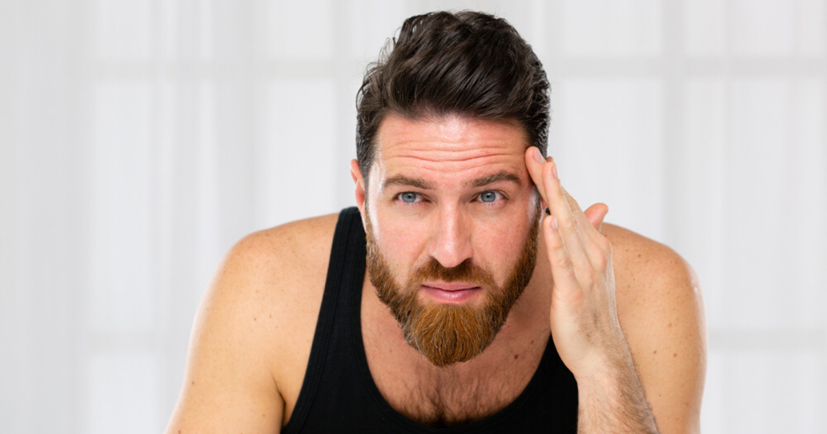 middle aged man using hairpiece maintenance techniques to bond front hairline