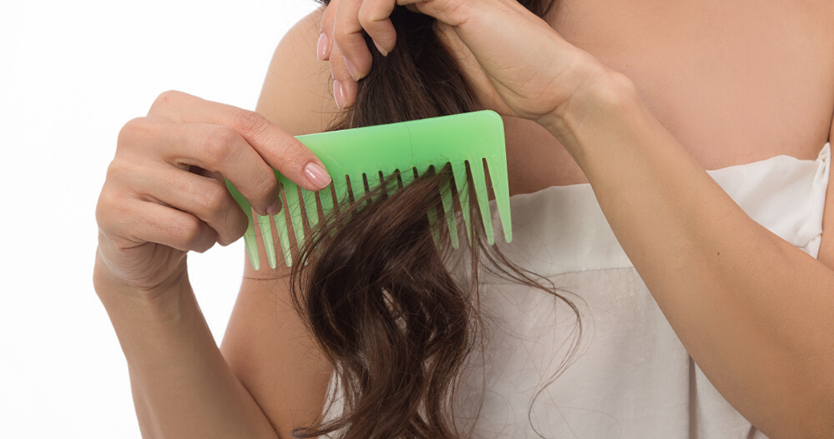 Woman combing hairpiece for good hair system care