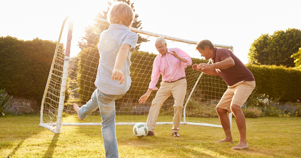 Middle aged man wearing hair system while playing soccer with family