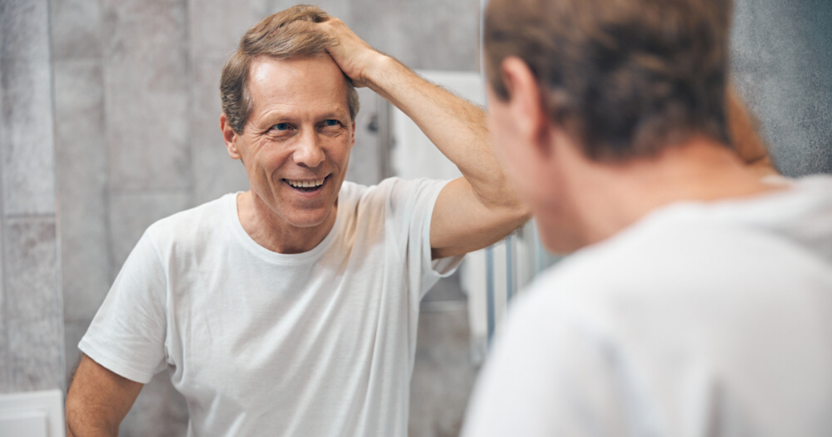 Middle aged man performing at home hair system application