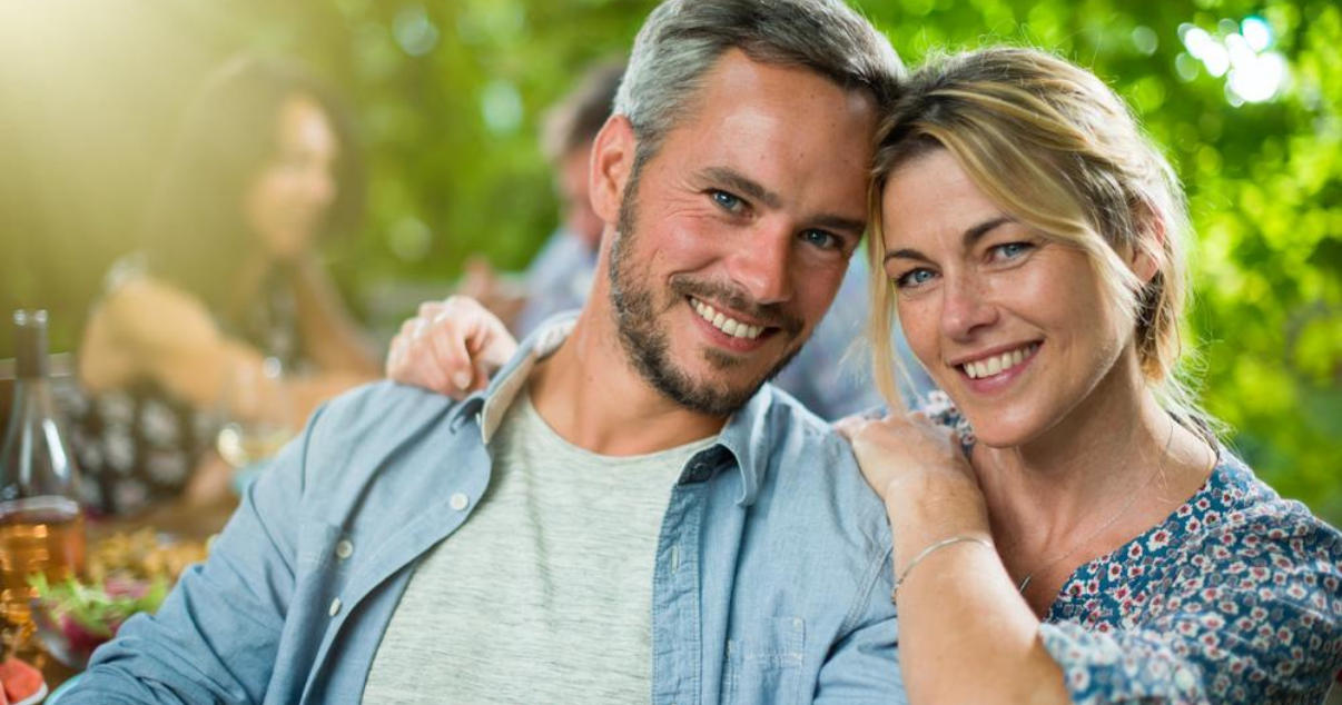 happy middle aged man with wife using glue on toupee