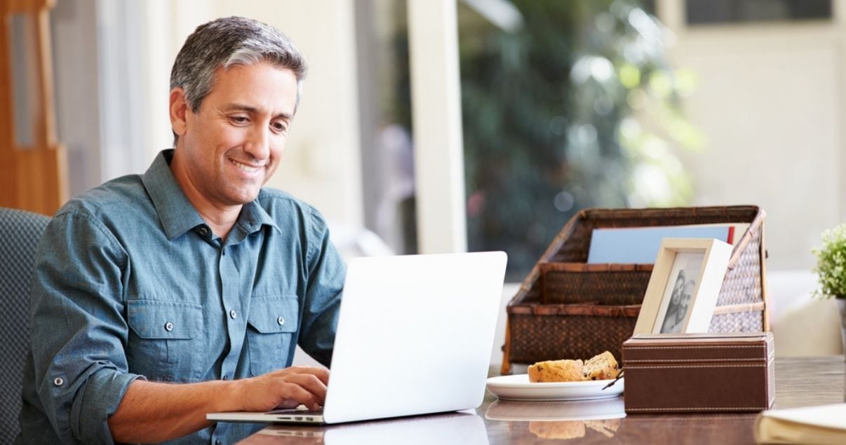 Mature man working at laptop and wearing toupee for men