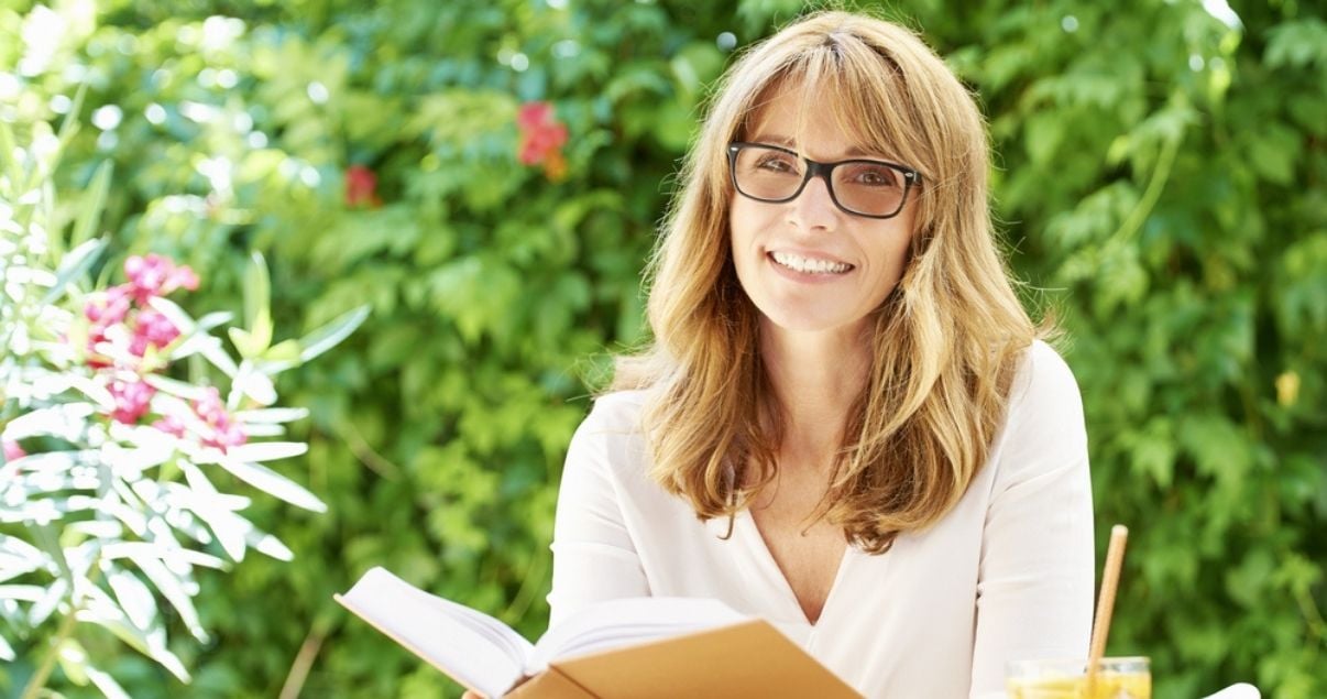 Smiling middle aged woman wearing best hair replacement system while reading
