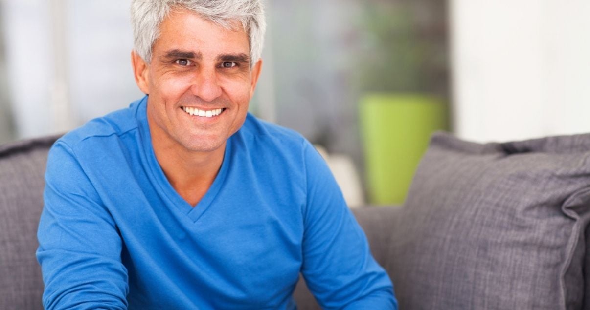 Smiling older man relaxing at home with hairpiece for men