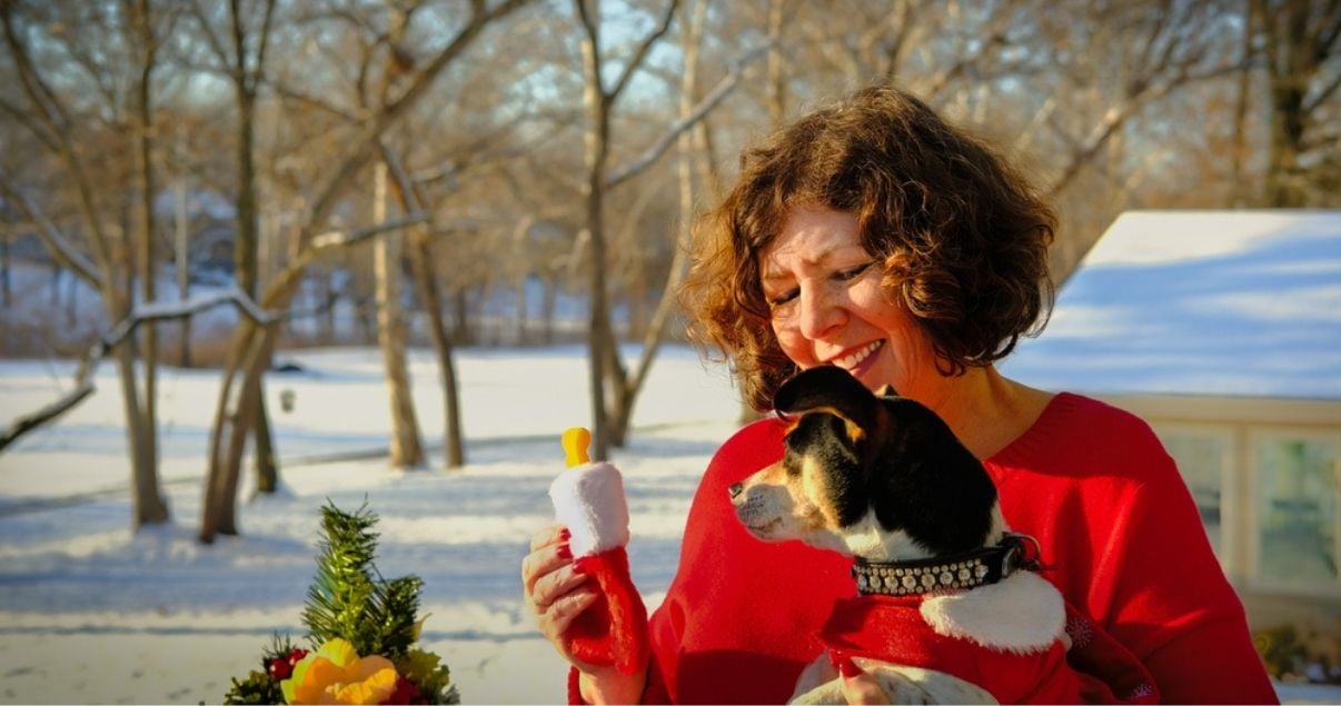 Middle aged woman in the snow with her dog using hairpiece maintenece techniques for long hairpiece lifespan