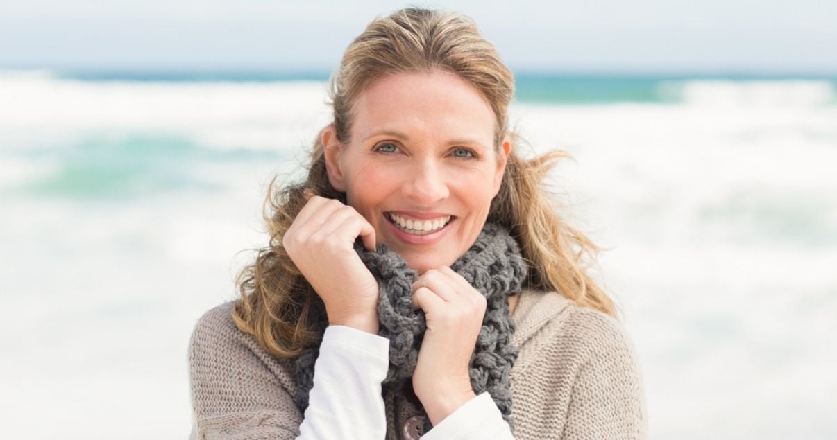 Smiling blonde woman on beach with good hairpiece maintenance