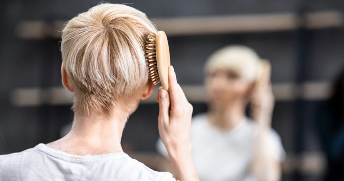 Middle aged woman brushing hair after using shampoo for wigs