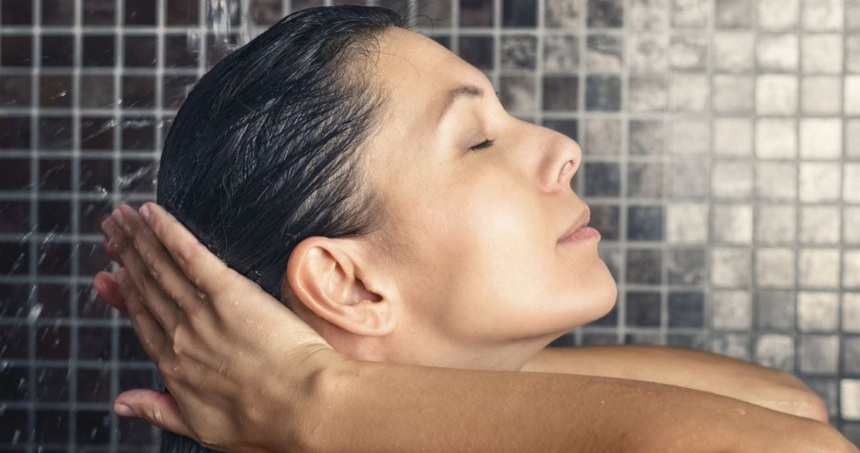 Middle aged woman using shampoo for wigs in the shower