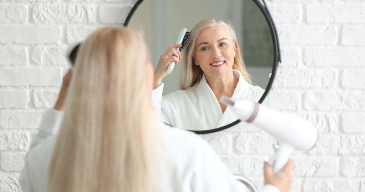 Older woman styling hair system in bathroom