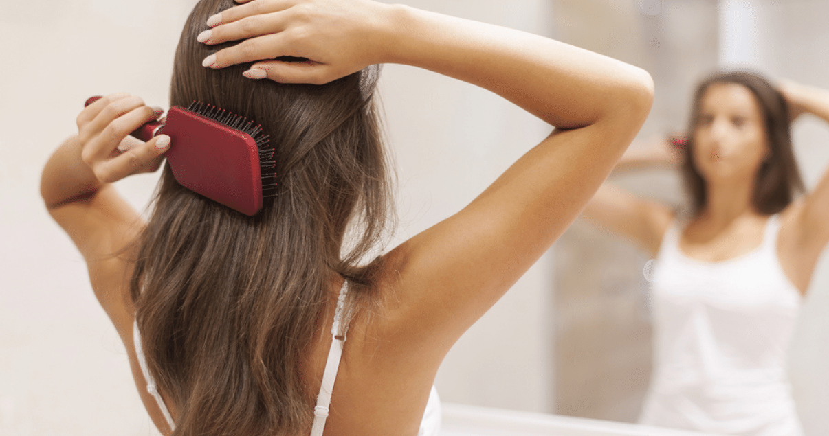 Middle aged brunette woman grooming hair before storing wig