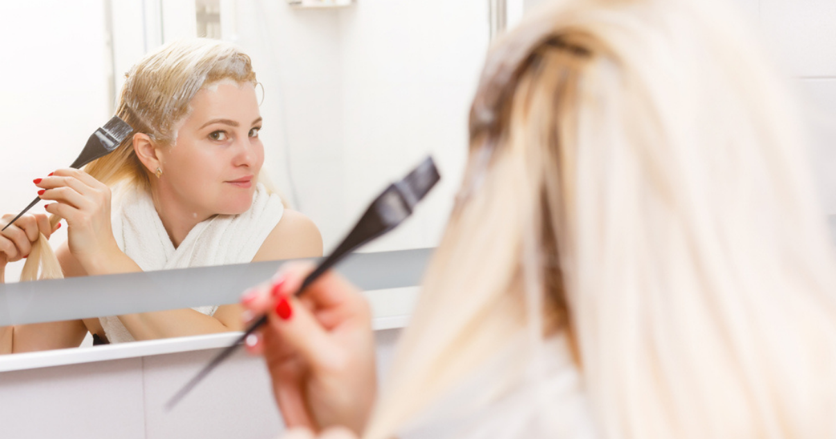 Blonde middle aged woman dyeing hair system as hairpiece maintenance