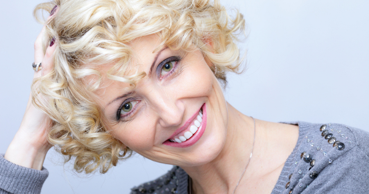 Blonde woman curling hair system at home