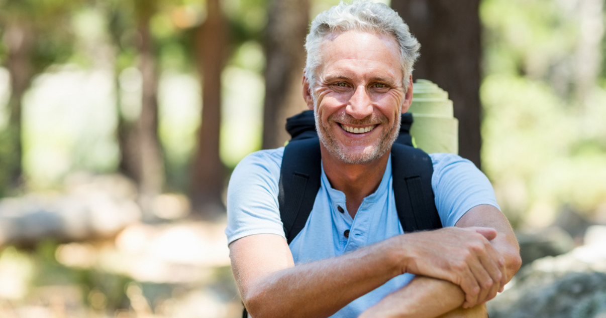 Happy man in the forest taking all the advantages that a toupee hair has to offer