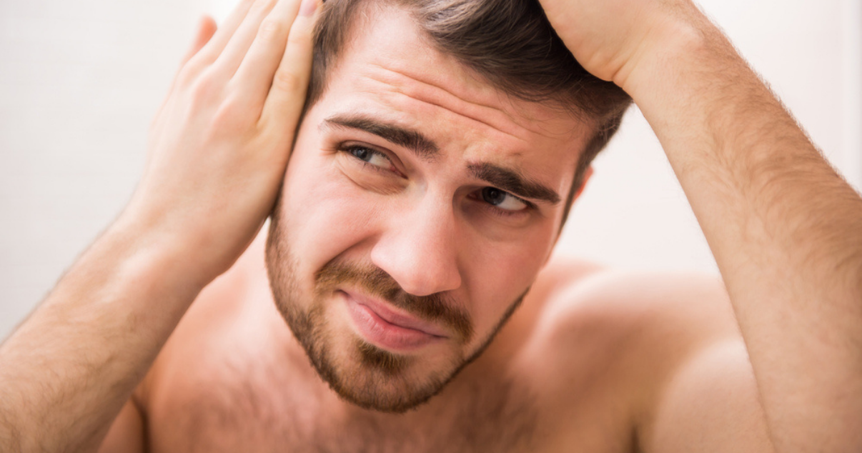 Man looking at himself in the mirror because of hairloss (1)