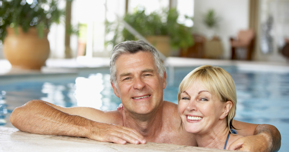 Middle age couple enjoying the pool while using hair replacement system