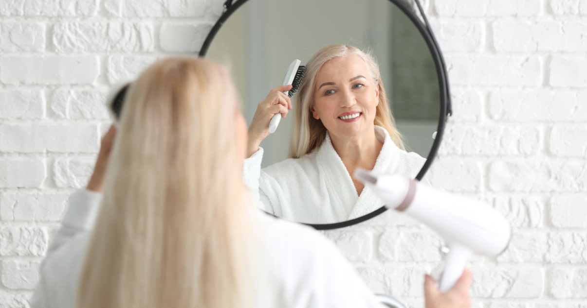 Middle aged woman drying hair system at home