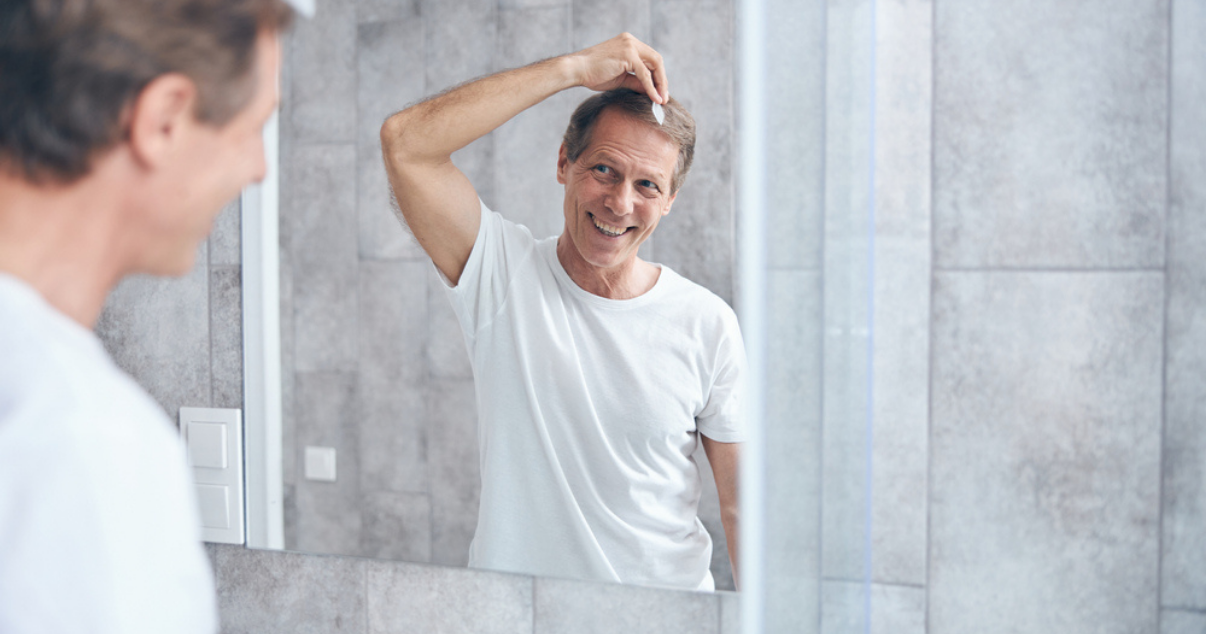 Older man doing hair system attachment at home without going to a hair studio