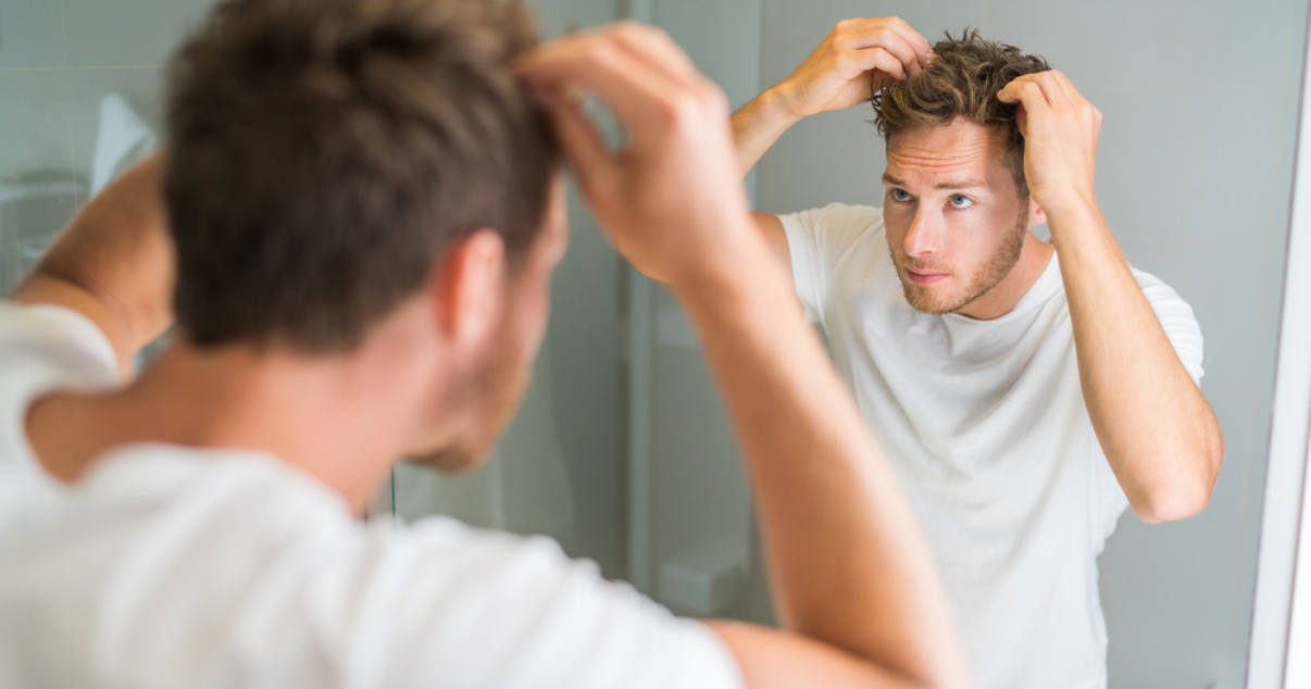 Young man using styling cream.