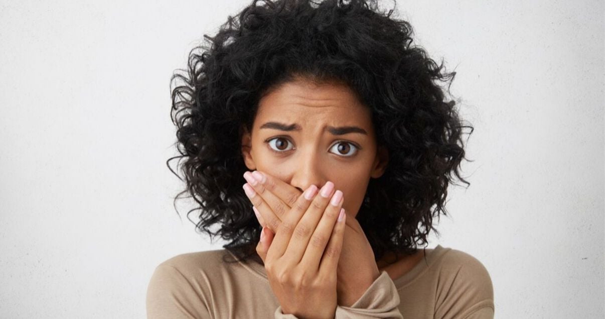 african woman holding her hands to her face worrying  about her hair system maintenance