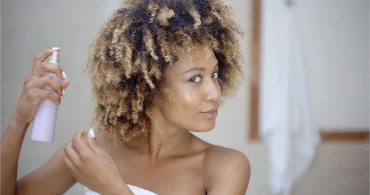 black woman spraying hair with styling tools