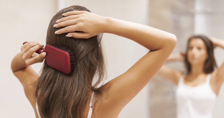 hair_system_maintence_brunette_women_brushing_long_hair_in_mirror