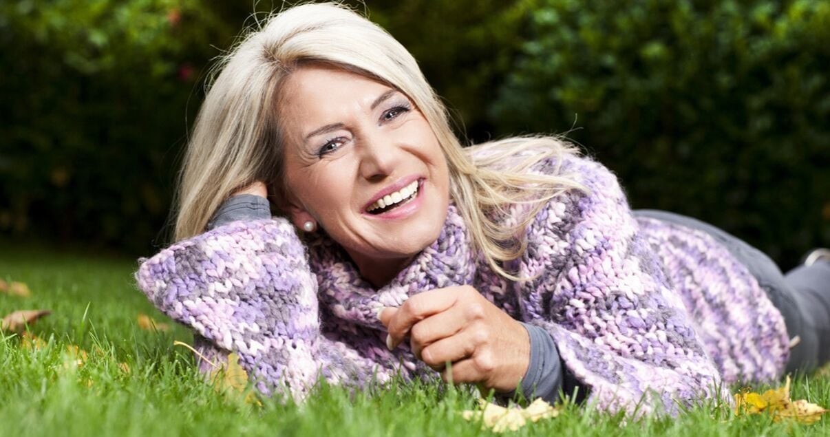 Middle aged woman laying on grass outdoors with her hairpiece with nice maintanence and odor