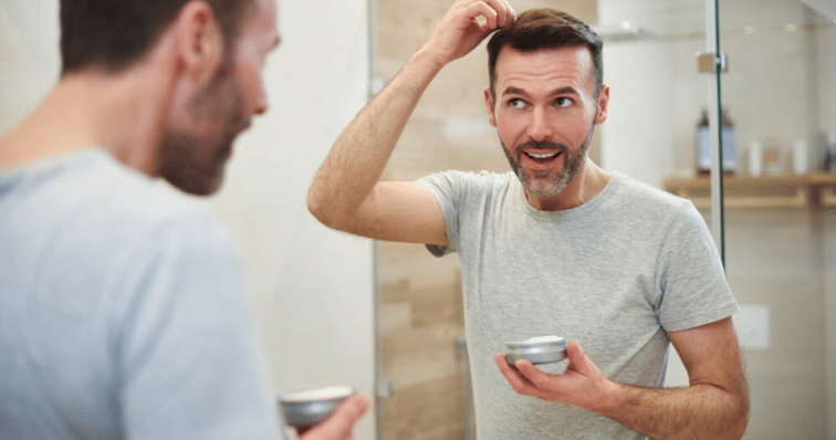 middle_aged_man_styling_attached_hair_system_with_liquid_adhesive_hair_piece_maintence