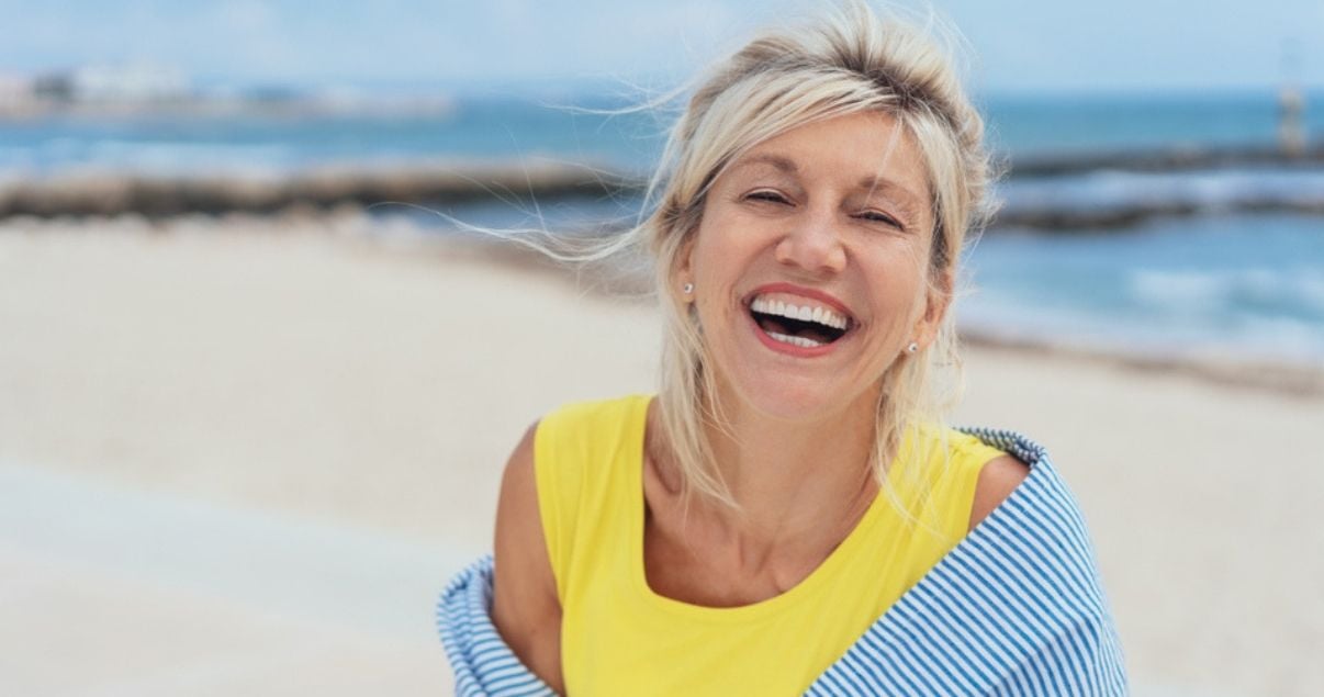 middle_aged_woman_walking_on_beach_enjoying_clean_hair_system_after_adhesive_removal