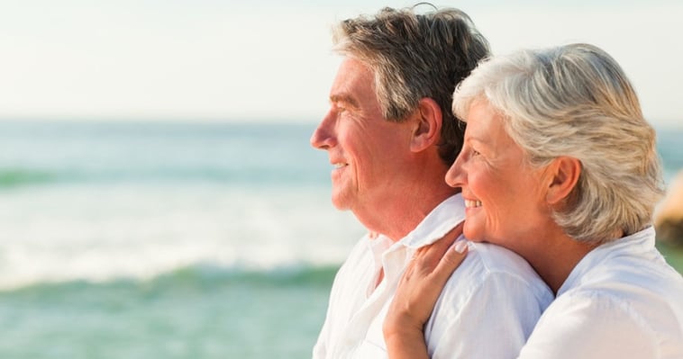 older man and woman at the beach happy about swimming with their hair system.