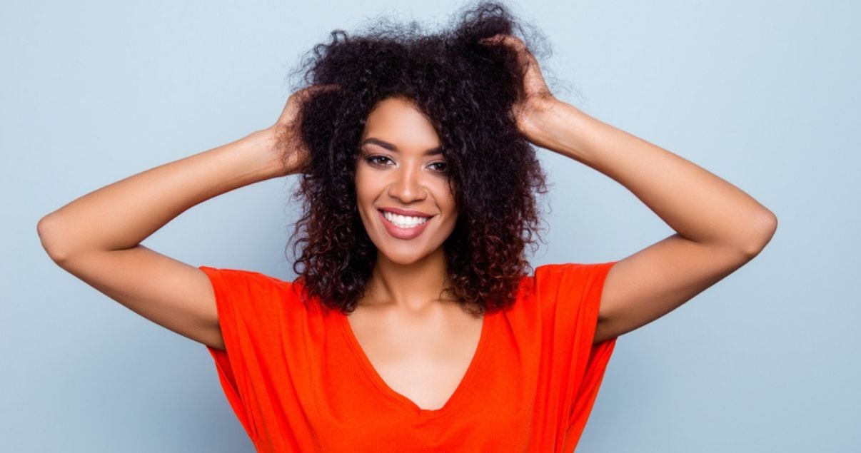 woman of color in vibrant shirt enjoying her soft hair system after adhesive removal