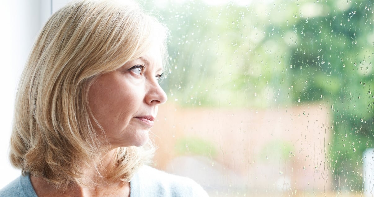middle aged woman looking out window