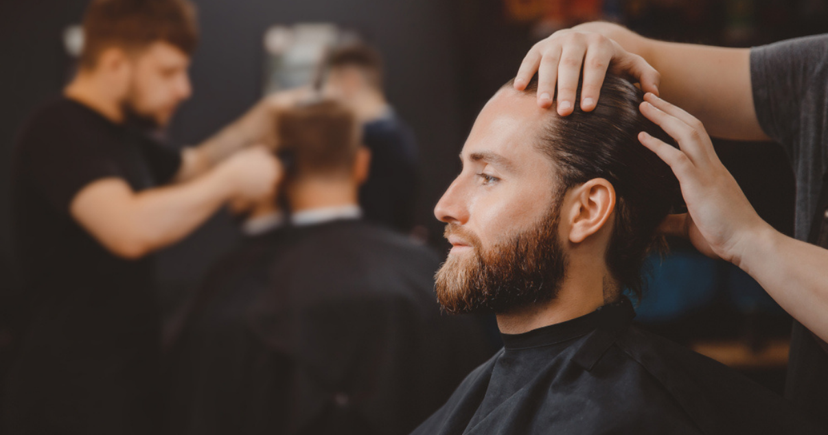 Man installing a hair piece at a hair salon.