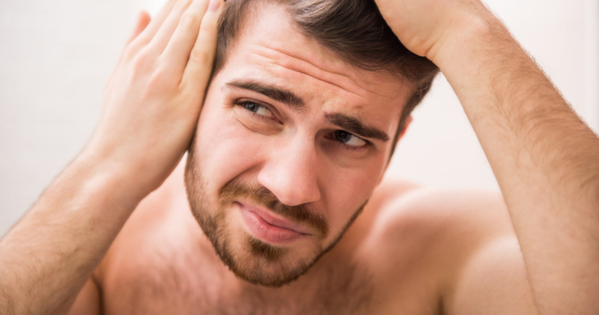 Man looking at himself in the mirror because of hairloss