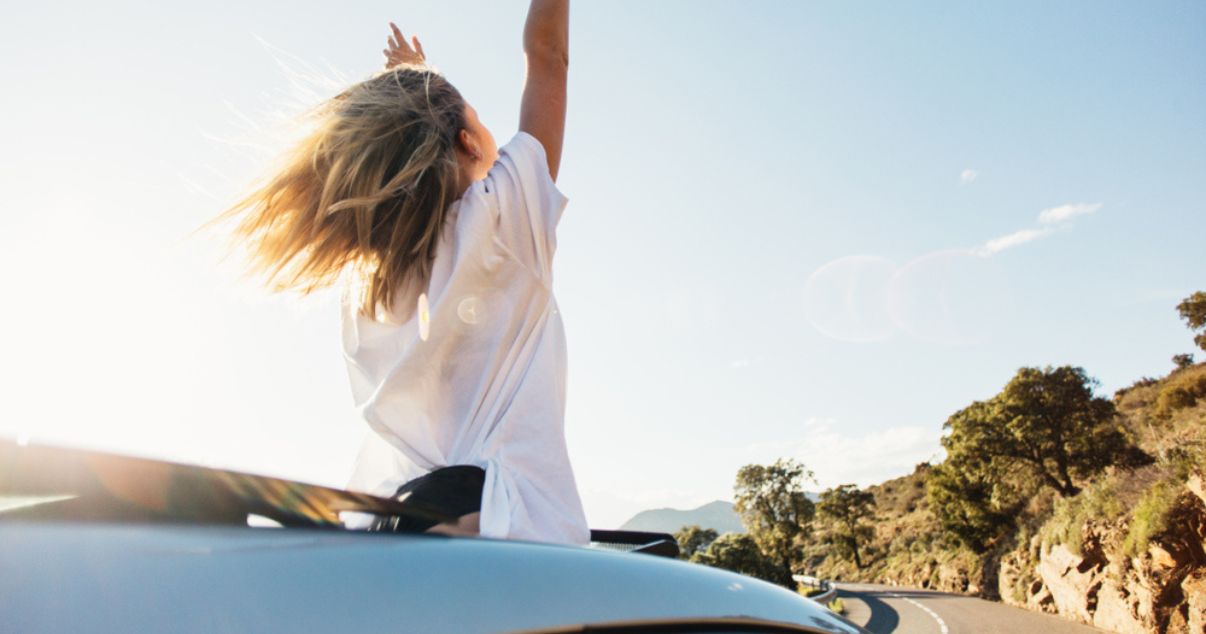 woman riding a car with her hairpiece in the summer wind